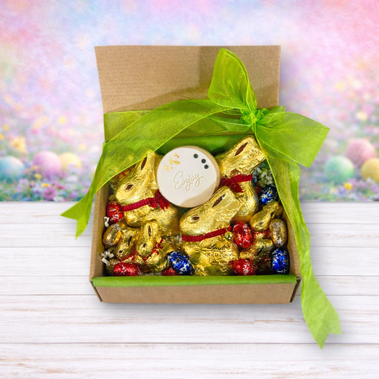 Box of gold chocolate bunnies with a green bow on a colorful blurred background