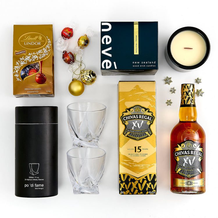 Collection of Chivas Regal XV whiskey, glasses, Lindt chocolate, and other items on a white background