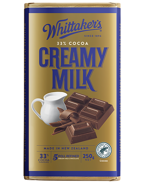 Packaging of Whittaker's Creamy Milk chocolate block with an image of a chocolate bar, a cup, and pieces of chocolate on a blue and gold background.